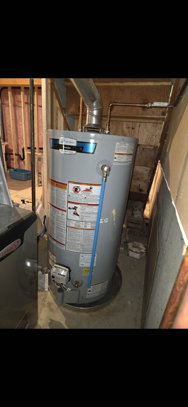 A new gas hot water tank with a blue flexible water line, vent pipe and copper piping