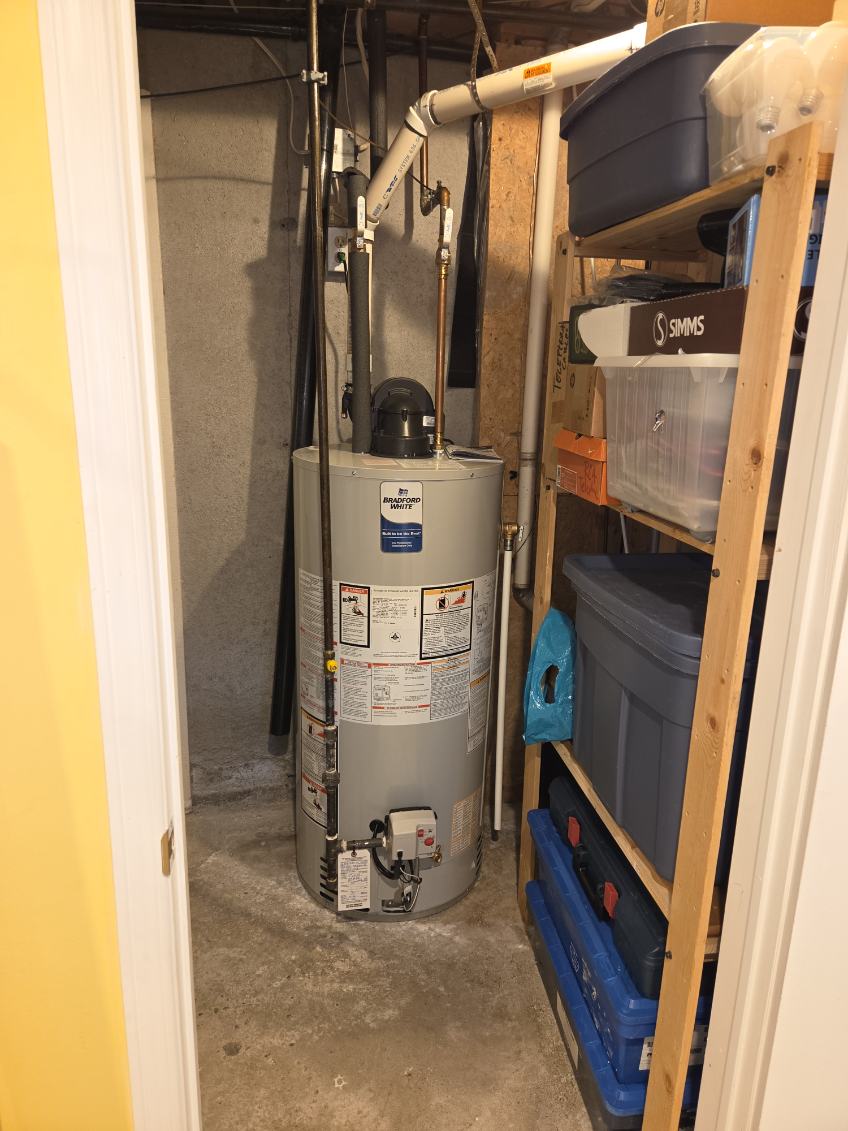 A power-vent hot water tank installed in a closet with gas and water connections